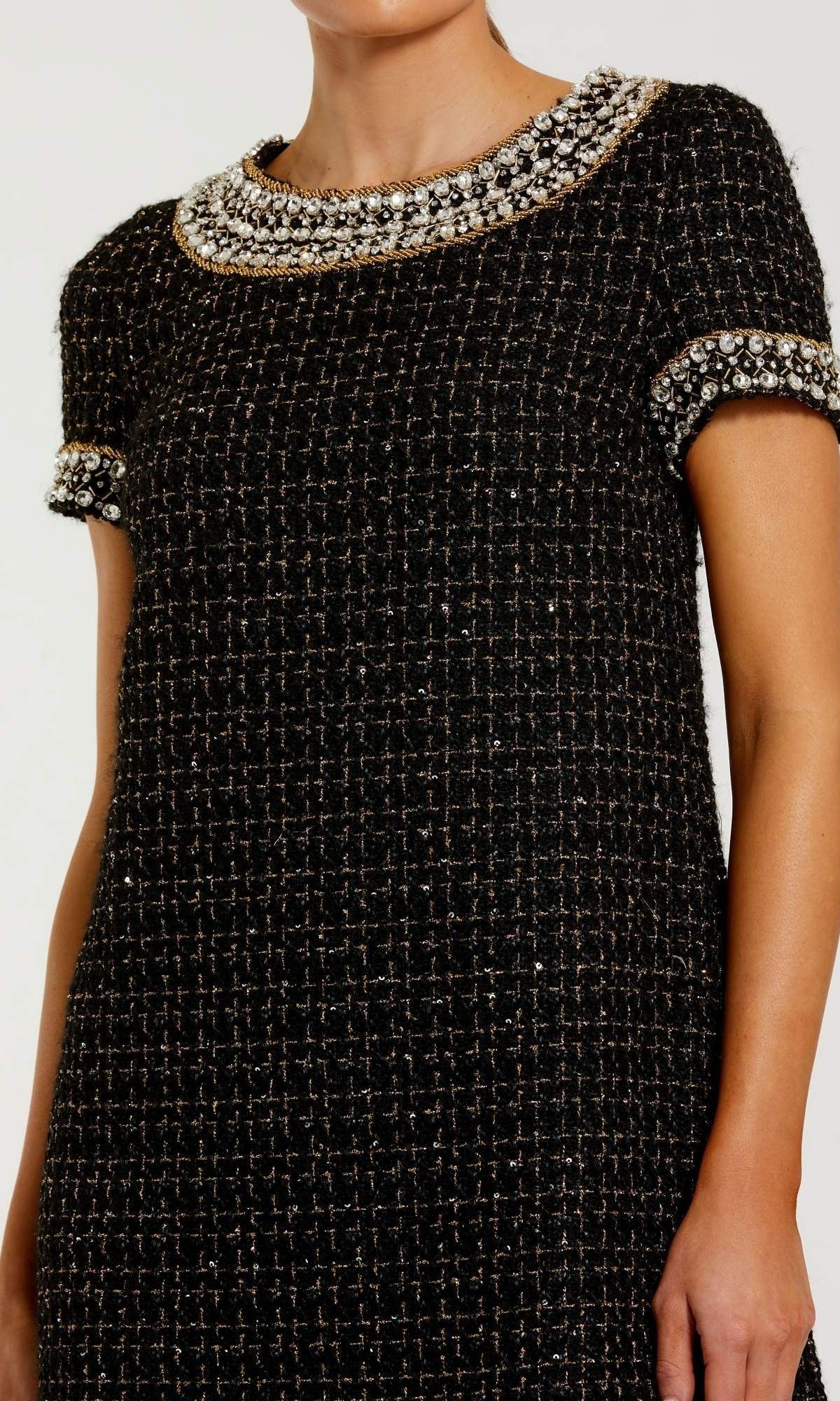 Wearing the Mac Duggal 37075 short semi-formal dress, a woman showcases a short-sleeve black boucle mini design adorned with pearl, rhinestone beading, and gem embellishments on the collar and cuffs.